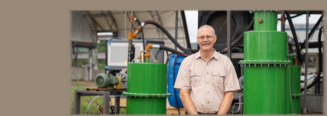 SUNY Cobleskill Assistant Professor David Waage in front of the inclined rotary gasifier