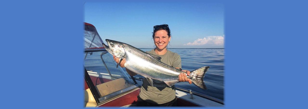 SUNY Oswego biological sciences faculty member Ellen Karboski holds an adult chinook caught on Lake Ontario
