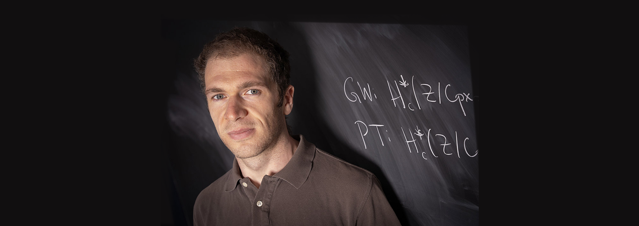Stony Brook University Professor John Pardon in front of a chalkboard with mathematical equation