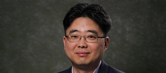Professional headshot of professor Seokheun Choi wearing rectangular eyeglasses and a dark blazer, facing the camera against a neutral gray background