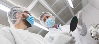 Researchers in cleanroom protective gear operating equipment in a nanofabrication lab