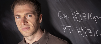 Stony Brook University Professor John Pardon in front of a chalkboard with mathematical equation