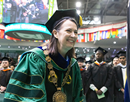 Binghamton University President Anne D'Alleva in green academic regalia and ceremonial chain inaugurated as the University’s eighth president, with graduates and international flags in the background during a formal investiture ceremony on Oct. 2, 2026