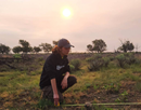 Binghamton University studen Madison Cardiel kneeling at the Amache National Historic Site, a former World War II Japanese internment camp in Colorado