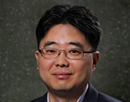 Professional headshot of professor Seokheun Choi wearing rectangular eyeglasses and a dark blazer, facing the camera against a neutral gray background