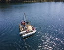Scientists lower a hollow metal tube (a freeze core) filled with dry ice and ethanol to collect sediment samples from the lake bottom. Like rings of a tree, each layer of sediment in Crawford Lake can be dated to a specific year