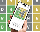 hand holding smartphone displaying the game wordle with large image of wordle in the background