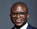 Professional headshot of assistant professor Brian McNeil in a suit and glasses against a gray background
