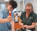 Professor Jennifer Gilbert Jenkins working with 16 year old Evan Buhain in the lab filling tubes