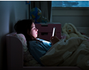 A child using a smartphone lying in bed