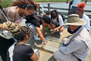 Five young men and woman crowd around a water-filled basin as a park ranger looks on
