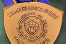 Chancellor’s Award for Excellence triangular medal on blue and gold ribbon