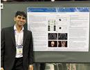 Conference attendee stands beside a research poster at an academic conference, posing next to a display of clinical images, charts, and study findings