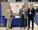 Assistant Professor Abolfazl Karimpour, at left, with Ellwood Hanrahan and Jared Winkens standing in front of a display of their presentation