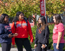A group of four female students on Stony Brook University campus with trees and a banner in the background