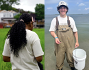 Two students participate in field research outdoors. One student faces away from the camera while another stands holding a white bucket in a grassy area
