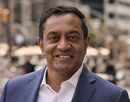 New York Climate Exchange Chief Executive Officer M. Sanjan in blue suite with a blurred city scape in the background