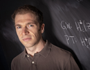 Stony Brook University Professor John Pardon in front of a chalkboard with mathematical equation