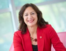 Stony Brook University President Andrea Goldsmith in black with a red jacket seated with a blurred background