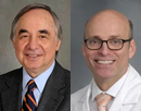 A side-by-side portrait of two men against gray backgrounds. The man on the left has gray hair and wears a dark suit, light blue shirt, and striped tie. The man on the right is bald, wears glasses, and is dressed in a white lab coat over a light shirt and pale tie. Both are smiling at the camera