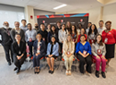 Group photo of attendees gathered indoors at a symposium or academic event, standing and seated together in a meeting room