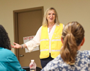 UAlbany’s Amy Nitza wearing a yellow high-vis vest and smiling addresses a participants at the start of the first full-scale immersive exercise of the Disaster Mental Health Training Program