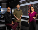 UAlbany researchers Sukanta Basu (left), Xin Li and June Wang stand in front of screens inside the xCITE Laboratory at ETEC