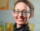University at Buffalo’s associate professor of geography Abigail Cooke, associate professor of geography in a gray turtleneck on an abstract background