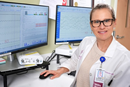 Healthcare professional seated at a workstation reviewing medical data on two computer monitors in a clinical office