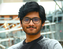 2026-27 Eberhard Research Fellow Bikram Aditya Das in a modern indoor space with blurred railings and lights in the background.