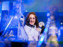 Researcher in a laboratory wearing safety glasses and gloves while working with scientific equipment under blue lighting