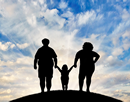 Silhouettes of three obese family members standing on a hill with a bright blue sky in the background.