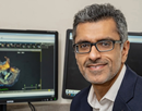 associate professor Ankur Kaira at a desk with monitors