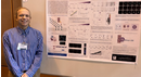 Researcher standing beside a scientific poster presentation at an academic conference