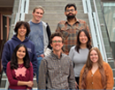 Group of seven researchers and students pose on a staircase inside a university building for a team photo