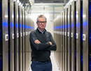 Hendrik Hamann standing with arms crossed between rows of server racks in a data center.